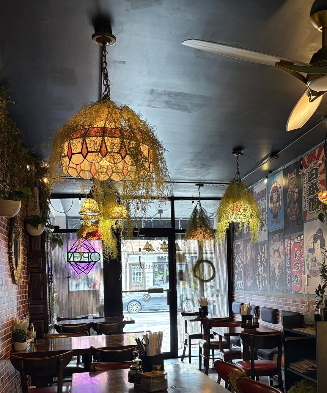 The cozy dining room at Mr. Noodle Café, with Tiffany lamps, brick walls, and wooden tables